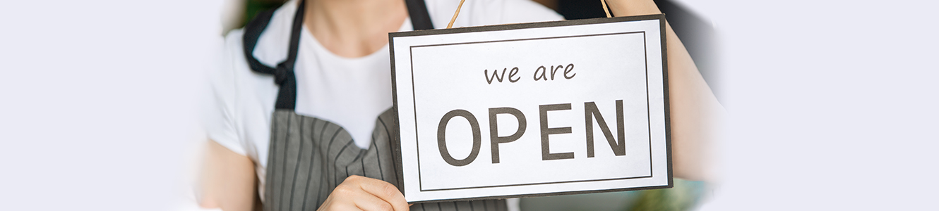 Woman holding "We Are Open" sign