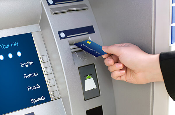 Image of someone putting their debit card into the ATM machine.